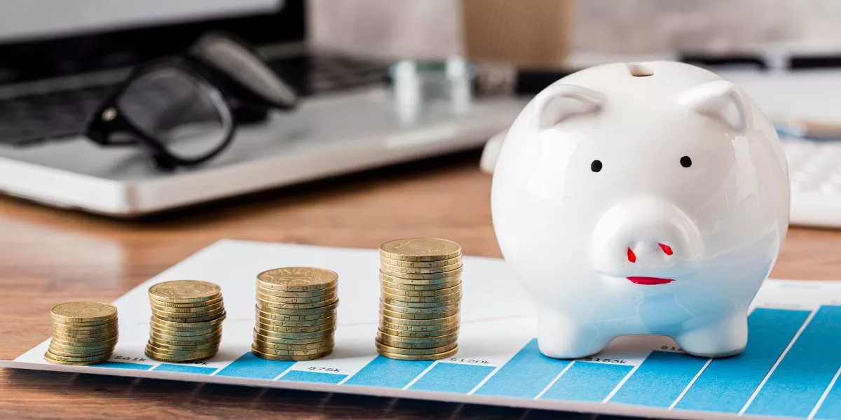 Alcancía con monedas sobre gráfico financiero y laptop de fondo representando el ROI en beneficios corporativos y ahorro fiscal en Uruguay