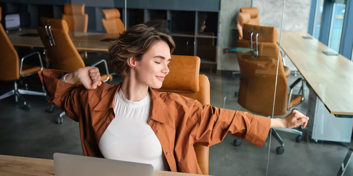 Colaboradora relajada disfrutando de sus beneficios laborales flexibles, en un entorno de trabajo moderno, enfocado en flexibilidad y bienestar